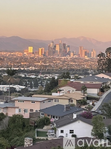 A cityscape with a mountain range in the background and a suburban neighborhood in the foreground.