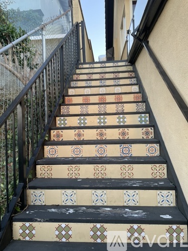 A set of stairs with a black railing and tiles with designs on them.
