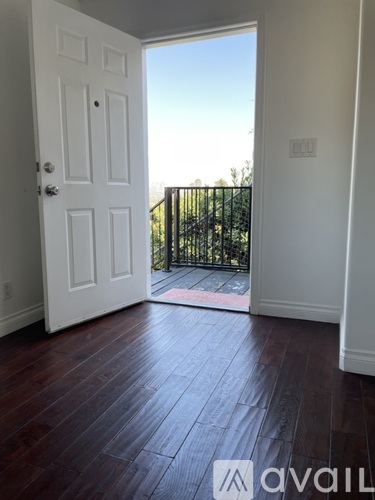 A room with a white door and wooden flooring.