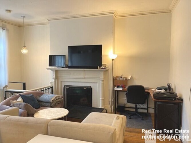 A living room with a fireplace and a television on the mantle.