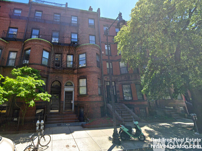 A red brick building with a tree in front.