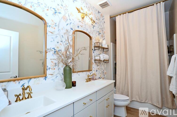 A bathroom with a floral wallpaper and a mirror above a sink.