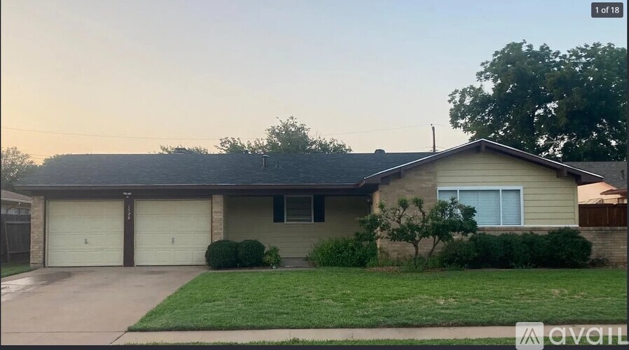 A house with a garage and a tree in front.