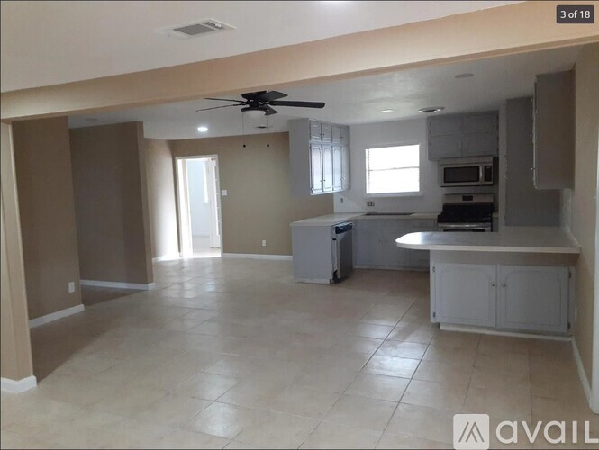 A kitchen with a fan on the ceiling and a dining area with a table and chairs.