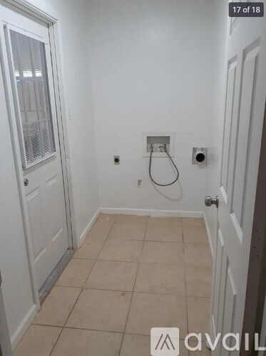 A bathroom with a white door and a white wall.