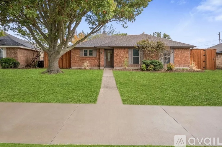 A house with a tree in front and a driveway leading to the front door.
