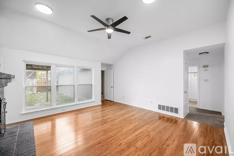 A spacious room with a ceiling fan and wooden flooring.