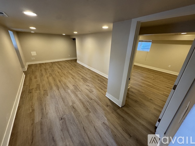 A spacious room with wooden flooring and white walls.