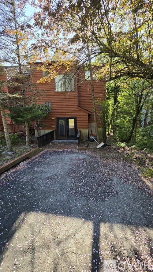 A driveway with a black gate and a brown house in the background.