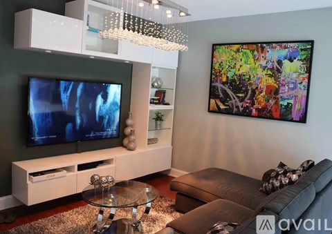 A modern living room with a television, a couch, and a painting on the wall.