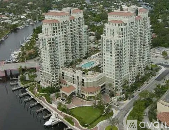 A large white building with a red roof is situated next to a body of water.