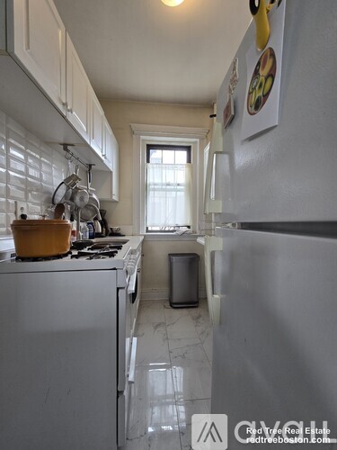 A kitchen with white appliances and a window.