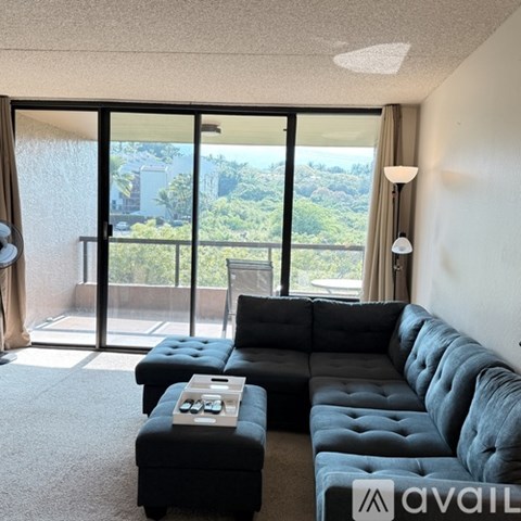A living room with a black couch and a coffee table in front of a large window.