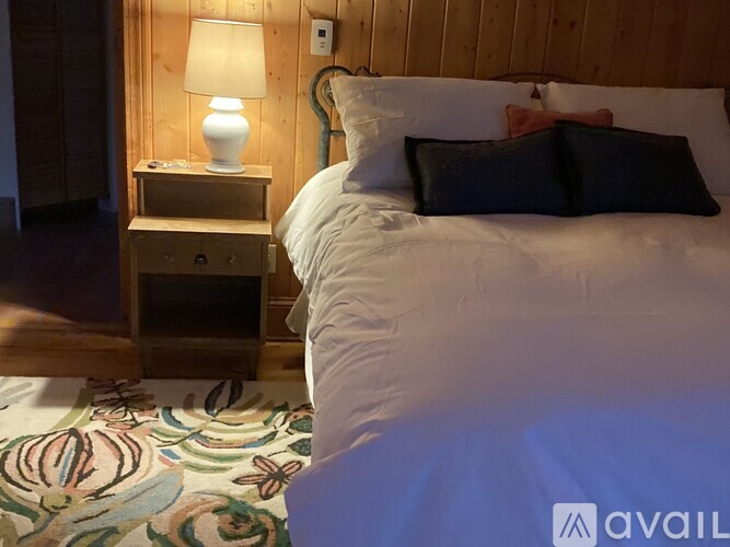 A bedroom with a bed, nightstand, and lamp.
