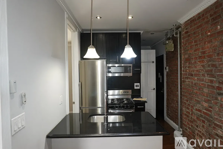 A kitchen with a black countertop and a stainless steel refrigerator.