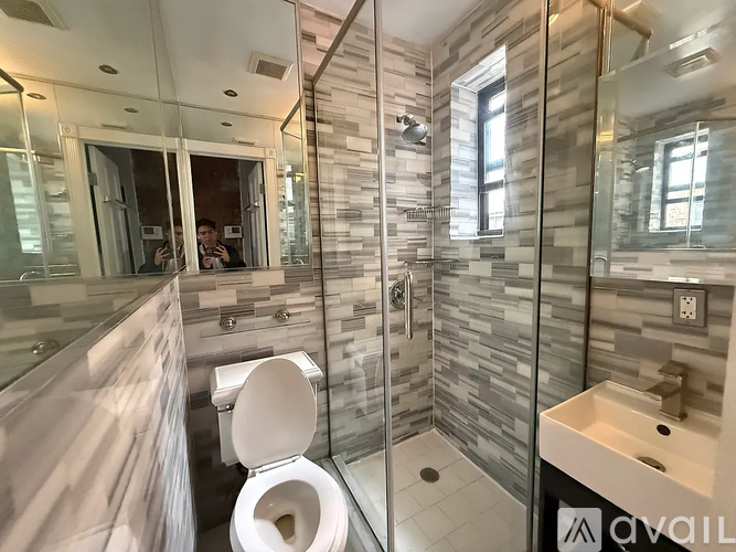 A bathroom with a toilet, sink, and glass shower stall.
