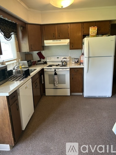 A kitchen with white appliances and brown cabinets.