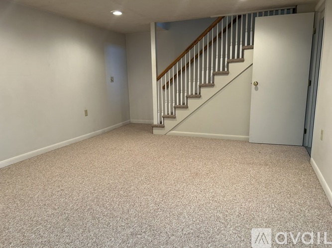 A spacious room with a staircase and carpeted floor.