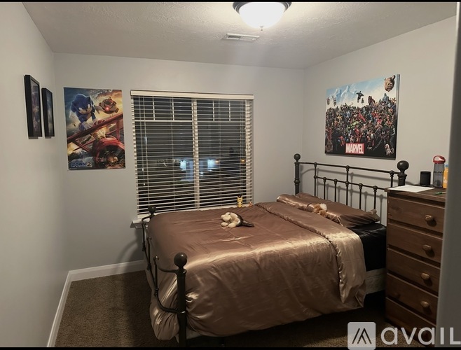 A bedroom with a bed, dresser, and two posters on the wall.