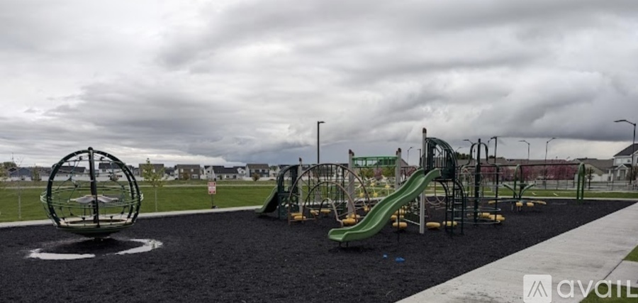 A playground with a green slide and a grey play structure.