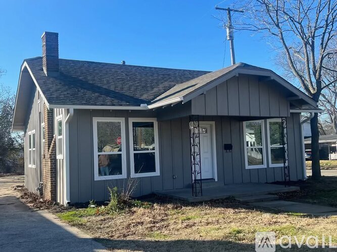 A small house with a grey exterior and a white door is for sale.