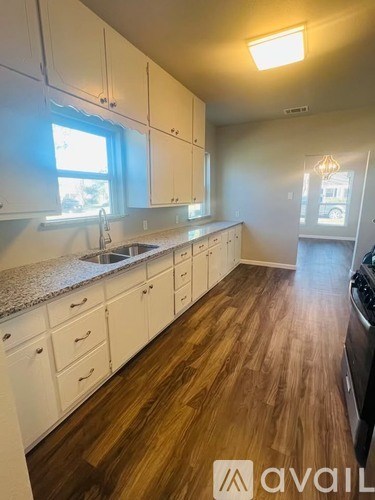 A kitchen with white cabinets and a wooden floor.