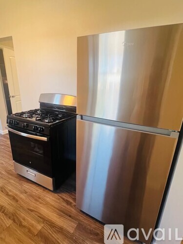 A stainless steel refrigerator stands next to a black stove in a kitchen.