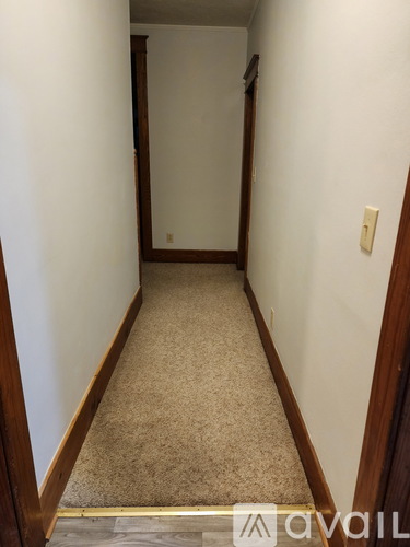 A hallway with a carpeted floor and white walls.