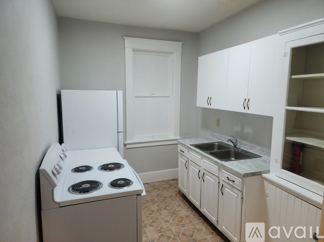 A small kitchen with a white stove and cabinets.