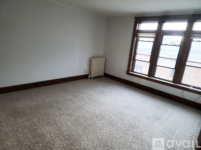 A room with a carpeted floor, a window, and a radiator.