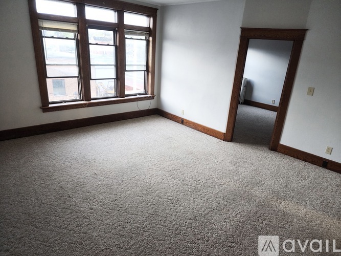 A room with a carpeted floor, a large window, and a door.