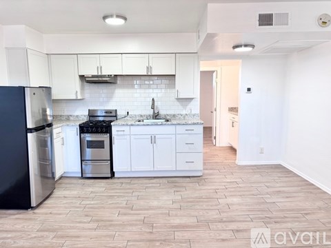 A kitchen with white cabinets and a black refrigerator.