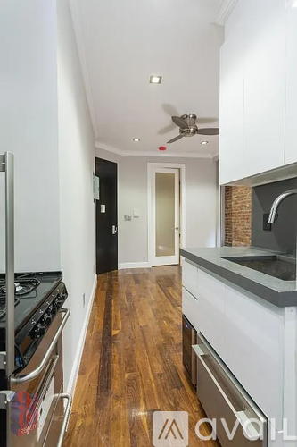 A kitchen with a stove top oven and a fan on the ceiling.