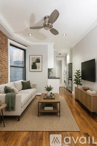 A living room with a white couch and a green throw blanket.