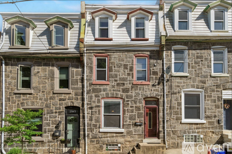 A row of stone houses with green shutters and red doors.