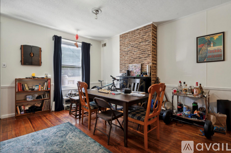 A room with a brick fireplace and a dining table set up with chairs.