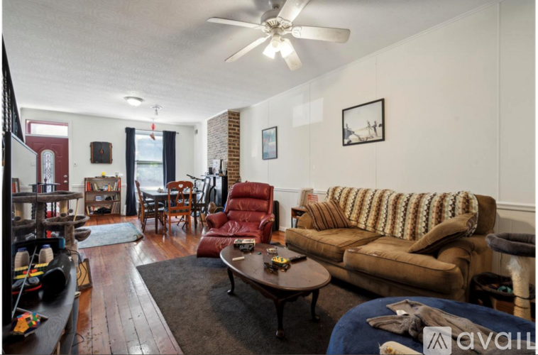 A living room with a brown couch and a ceiling fan.