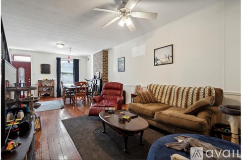 A living room with a brown couch and a ceiling fan.
