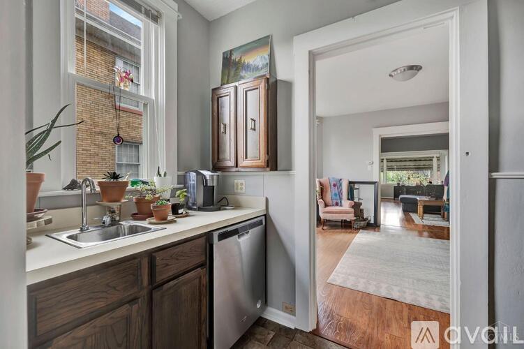 A kitchen with a sink, stove, and cabinets with a view of the living room.