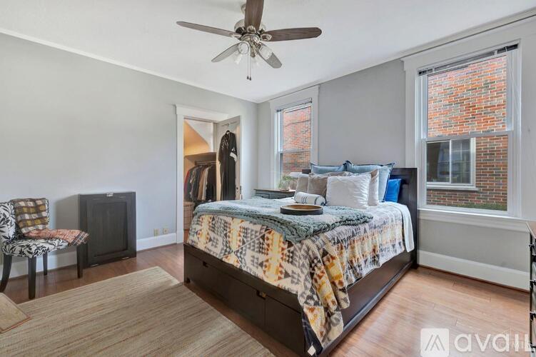 A bedroom with a bed, chair, and a ceiling fan.