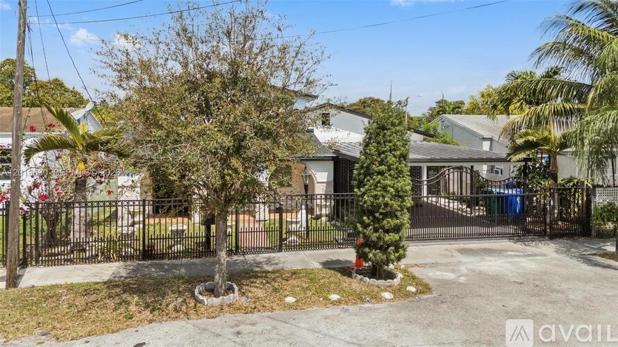 A house with a black fence and a tree in front.