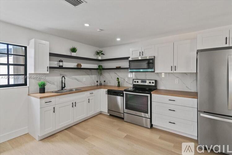 A modern kitchen with white cabinets and stainless steel appliances.
