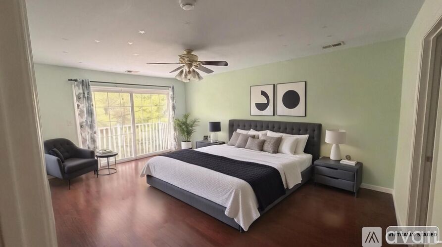 A bedroom with a large bed, a chair, and a ceiling fan.
