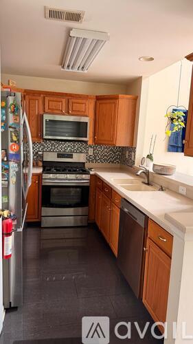 A kitchen with wooden cabinets and a black floor.