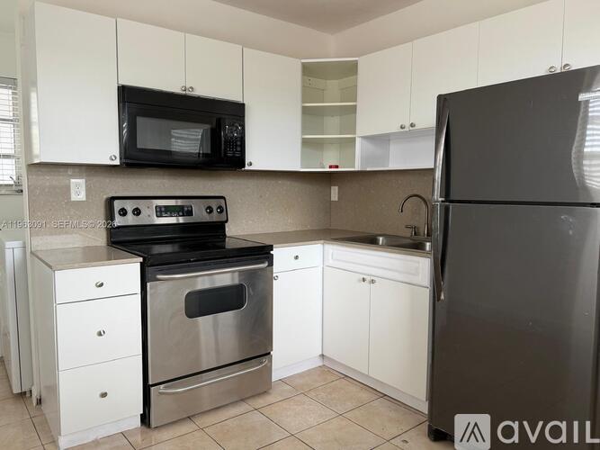 A kitchen with white cabinets and a black refrigerator.