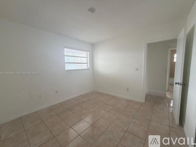 A room with a tiled floor and a window with blinds.
