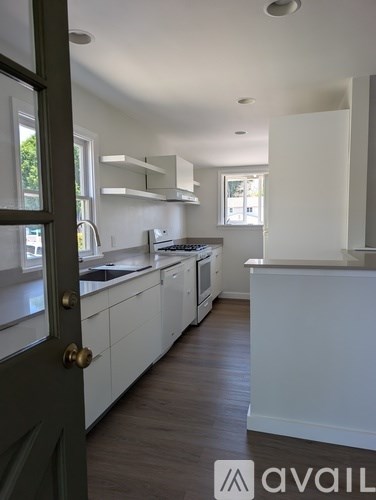 A kitchen with white cabinets and a black door.