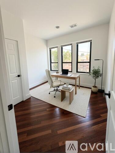 A room with wooden floors and a large window with a view of a building.