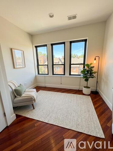 A room with a striped chair and a rug in front of a window.
