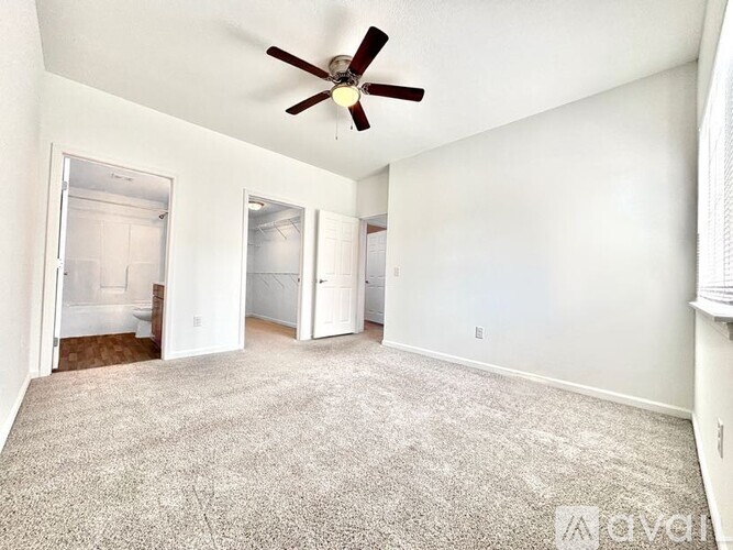 A room with a ceiling fan and carpeted floor.
